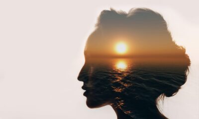 female head silhouette with sunset over sea reflection