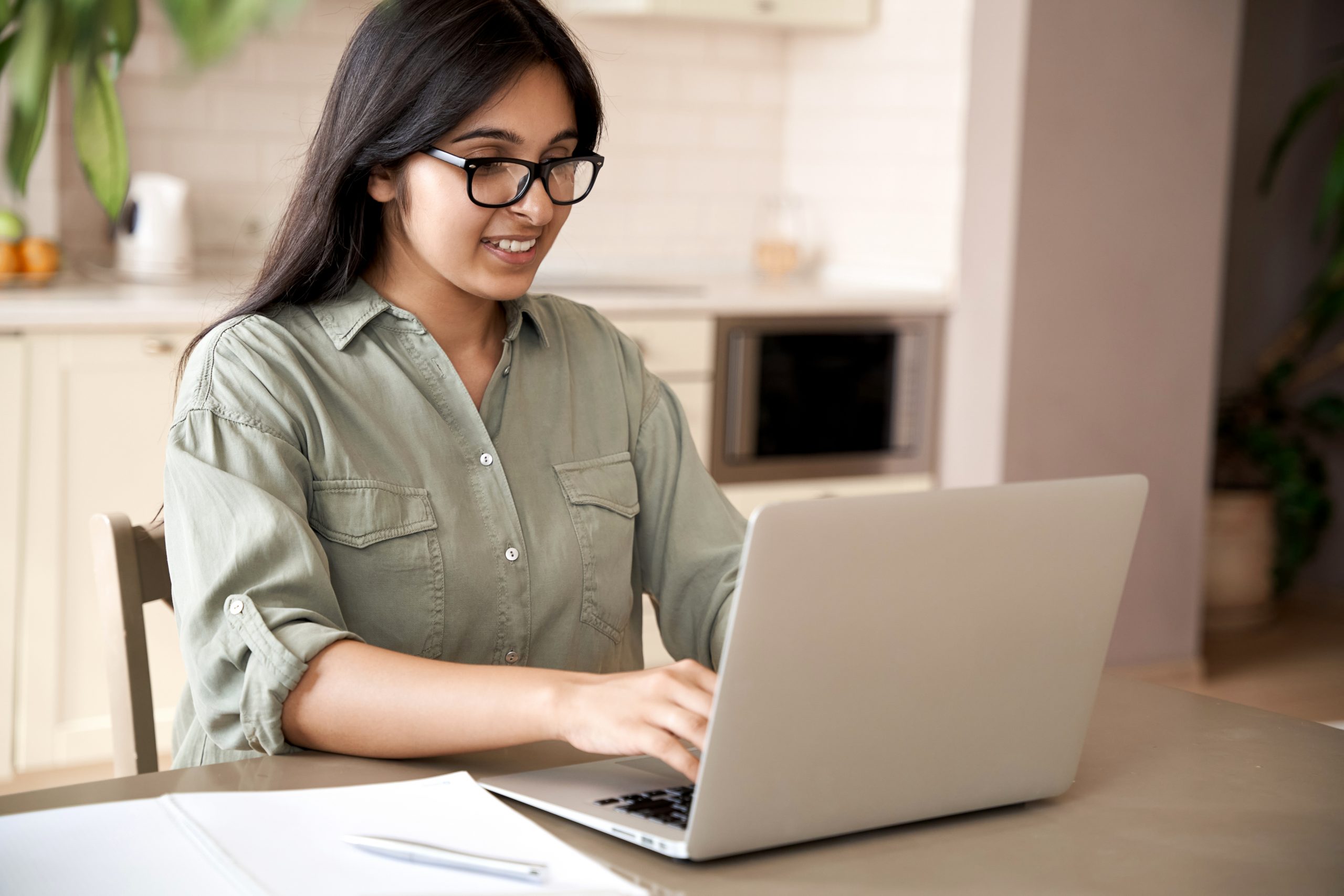 female teenager looking at laptop and making notes